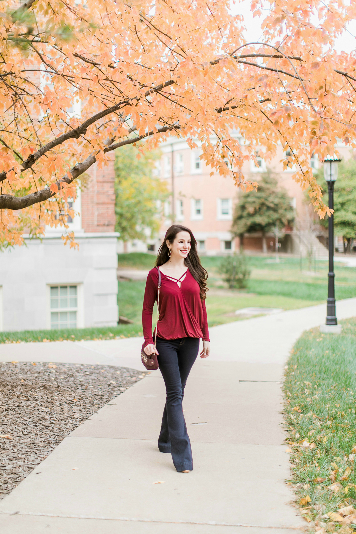 Long sleeve burgundy surplice top with dark wash flare jeans | Casual Thanksgiving outfit idea | What to Wear Out on Thanksgiving Eve by fashion blogger Stephanie Ziajka from Diary of a Debutante
