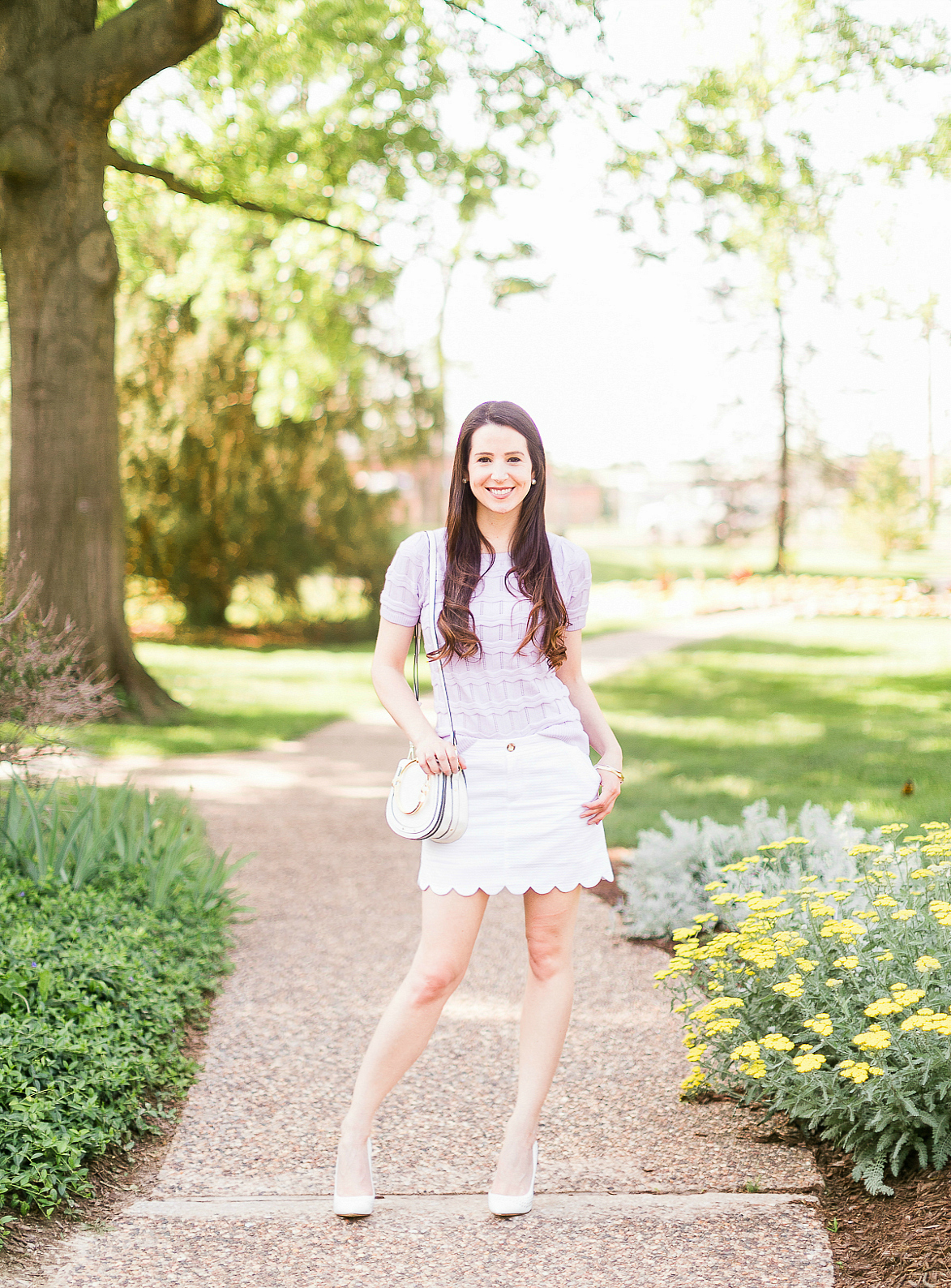 How to wear a short sleeve sweater in the spring by southern fashion blogger Stephanie Ziajka from Diary of a Debutante, lilac Cable Stitch short sleeve sweater, Lilly Pulitzer scalloped mini skirt, white Chloe Nile dupe bag, Chloe dupe bags, Kendra Scott mixed metal bangle set