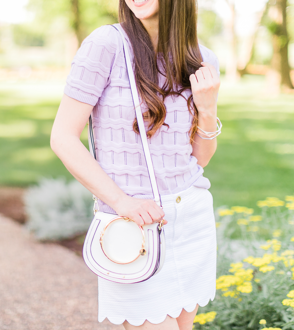 How to wear a short sleeve sweater in the spring by southern fashion blogger Stephanie Ziajka from Diary of a Debutante, lilac Cable Stitch short sleeve sweater, Lilly Pulitzer scalloped mini skirt, white Chloe Nile dupe bag, Chloe dupe bags, Kendra Scott mixed metal bangle set