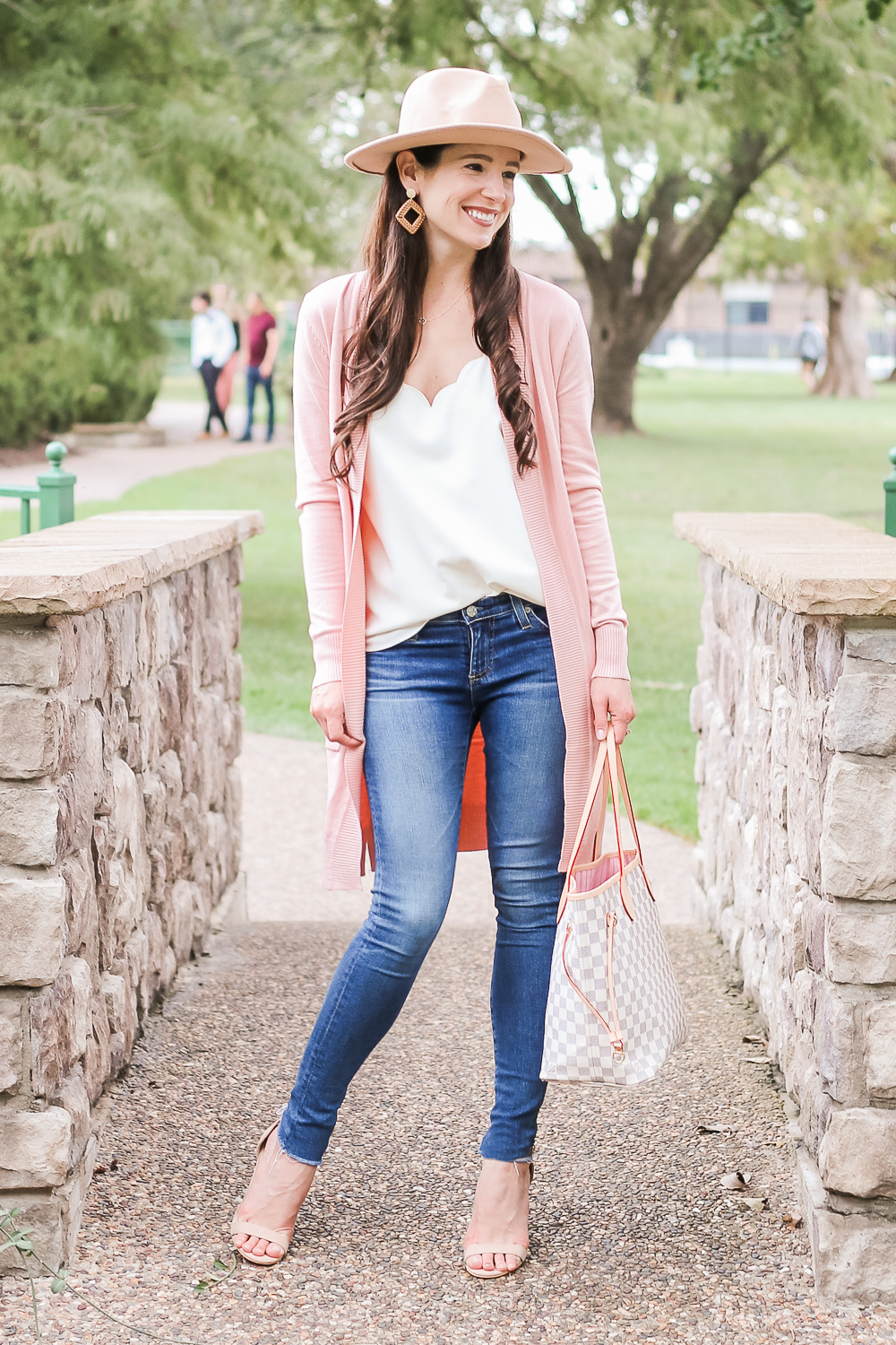 Casual Pink Cardigan Outfit styled by popular affordable fashion style blogger Stephanie Ziajka on Diary of a Debutante, Amazon light pink cardigan styled with J.Crew Factory scalloped cami top, AG the Legging super skinny jeans, Amazon Lanzom wide brim wool fedora hat, Amazon Louis Vuitton Neverfull dupe bag, Amazon nude block heel sandals, Amazon rattan earrings, and Amazon gold circle pendant necklace by Stephanie Ziajka on Diary of a Debutante