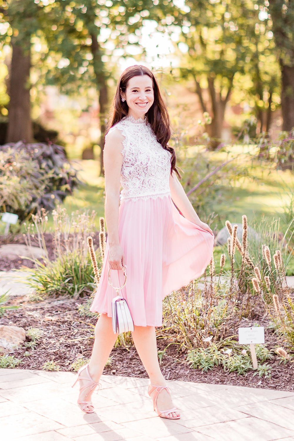 Day to Night: How to Wear a Pink Midi Skirt in the Fall by popular affordable fashion blogger Stephanie Ziajka on Diary of a Debutante, Amazon pink pleated midi skirt styled with an Amazon white lace crop top, white Chloe Nile dupe bag, and pink Nina Cherie dress pumps