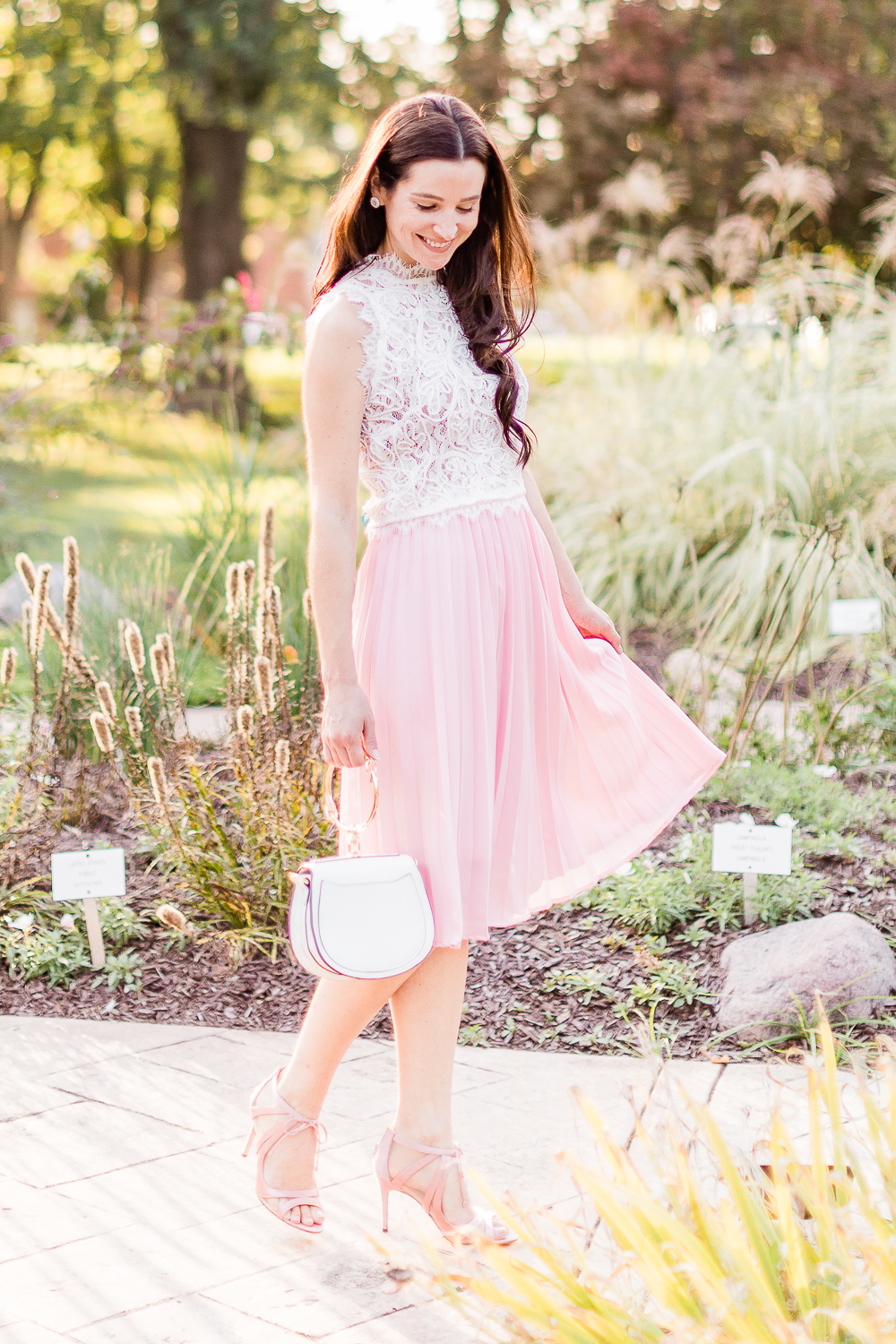 Day to Night: How to Wear a Pink Midi Skirt in the Fall by popular affordable fashion blogger Stephanie Ziajka on Diary of a Debutante, Amazon pink pleated midi skirt styled with an Amazon white lace crop top, white Chloe Nile dupe bag, and pink Nina Cherie dress pumps