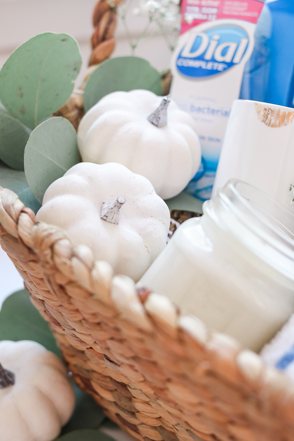 Adding small white pumpkins to a gift basket, how to decorate a fall gift basket