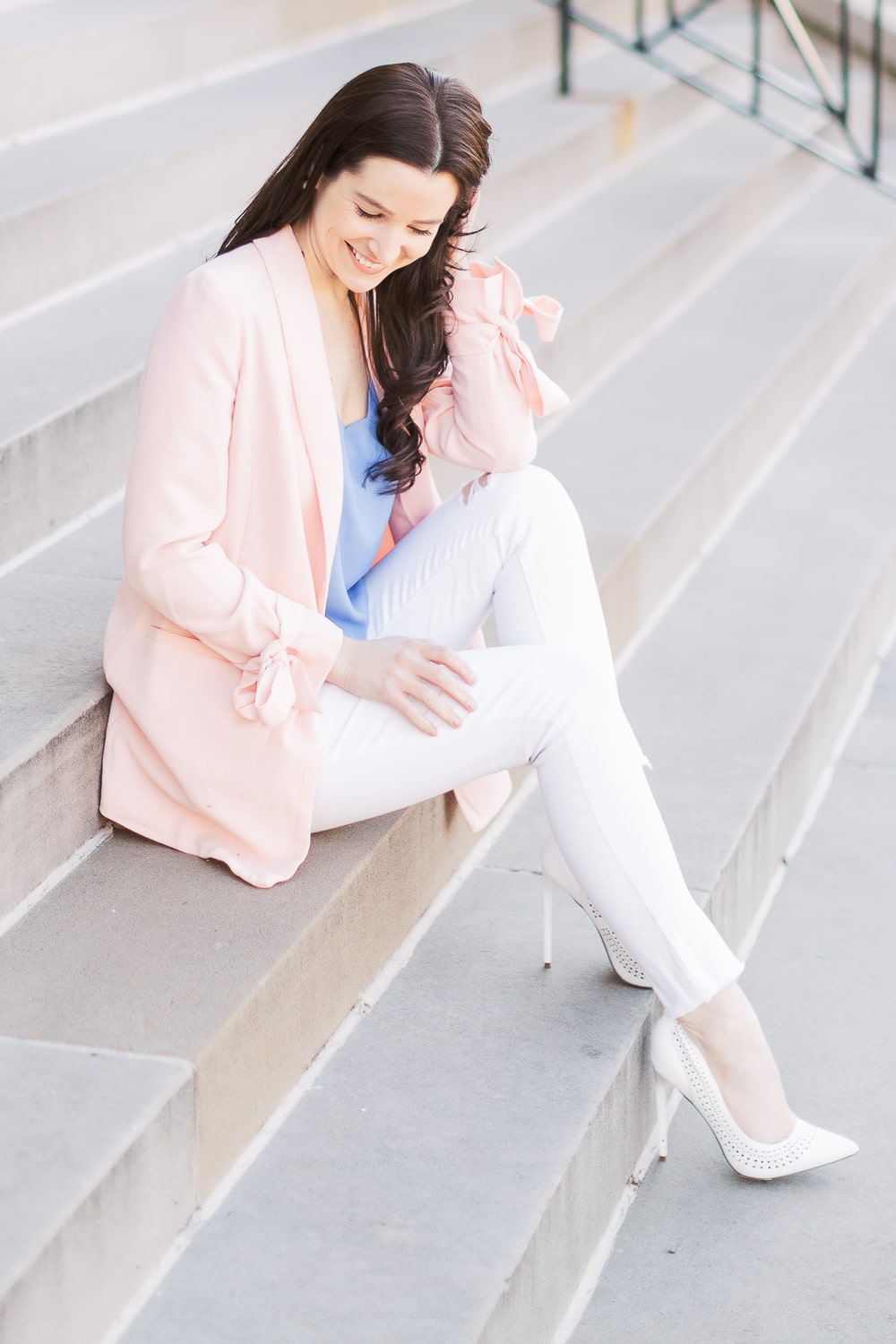 Affordable fashion blogger Stephanie Ziajka styles a pink bow sleeve blazer with Levi women's 721 high rise skinny ankle jeans, J.Crew Factory blue scalloped cami, and white perforated pumps
