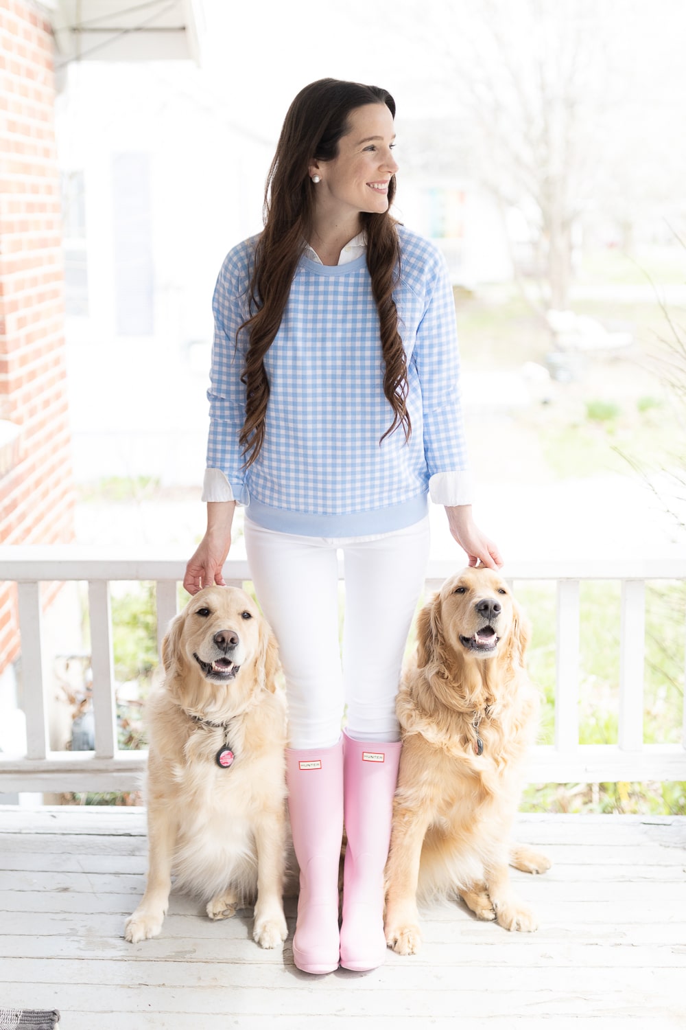 Preppy fashion blogger Stephanie Ziajka and her two golden retrievers show how to wear pink rain boots by styling matte pink Hunter Boots with a blue gingham Draper James sweater and white Levi's 711 skinny jeans on Diary of a Debutante