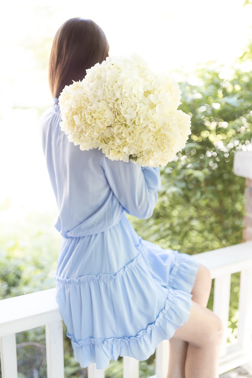Blogger Stephanie Ziajka holds a bouquet of white hydrangeas on Diary of a Debutante
