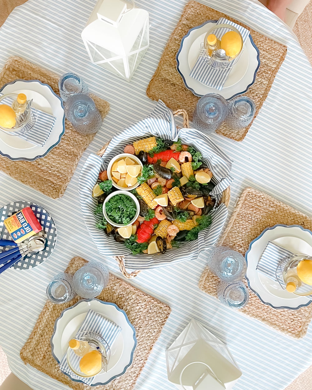 Blogger Stephanie Ziajka designed this simple summer tablescape using natural jute placemats, blue Villeroy and Boch goblets, and white and blue scalloped dinner plates on Diary of a Debutante